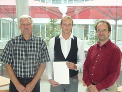 Prof. Dr. Stephan Herminghaus, Direktor am MPIDS, (rechts) und Ausbildungsleiter Joachim Hesse (links) überreichten die Urkunde an Robin Zemmrich (Mitte).