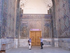 Die Organisatoren der Konferenz, Prof. Dr. Theo Geisel (links) und Prof. Dr. Davron Matrasulov (rechts), deuten auf das Tagungsbanner, das über der reichverzierten Tür der Ulugbek-Madrasa hängt.