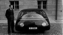 Einzigartiges Auto mit glänzender Oberfläche und abgerundeten Scheinwerfern, Nummernschild IS-20611 vor einem Gebäude mit Fenstern und gepflastertem Boden.